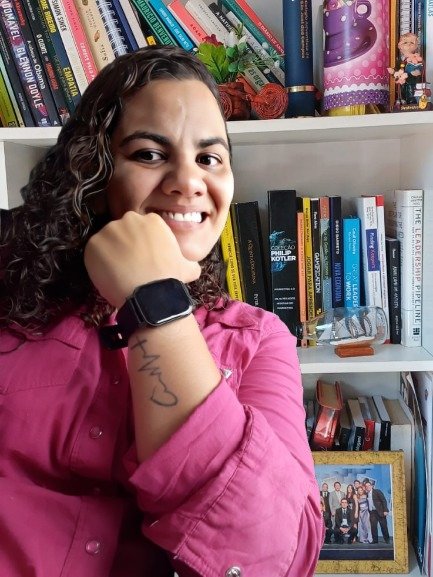 Élita Silva, anfitriã do clube, em frente à sua estante